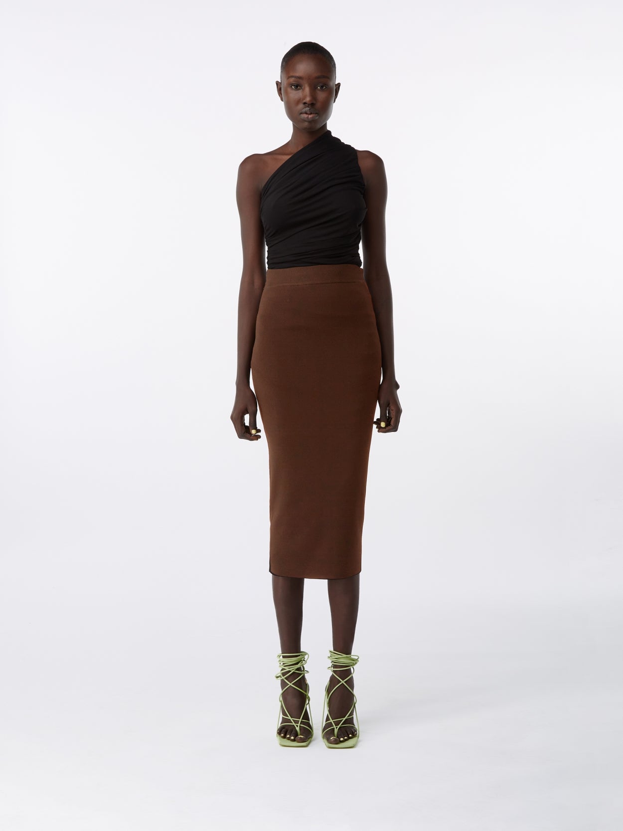 model wearing a black one shoulder draped jersey bodysuit and a brown midi knit pencil skirt 