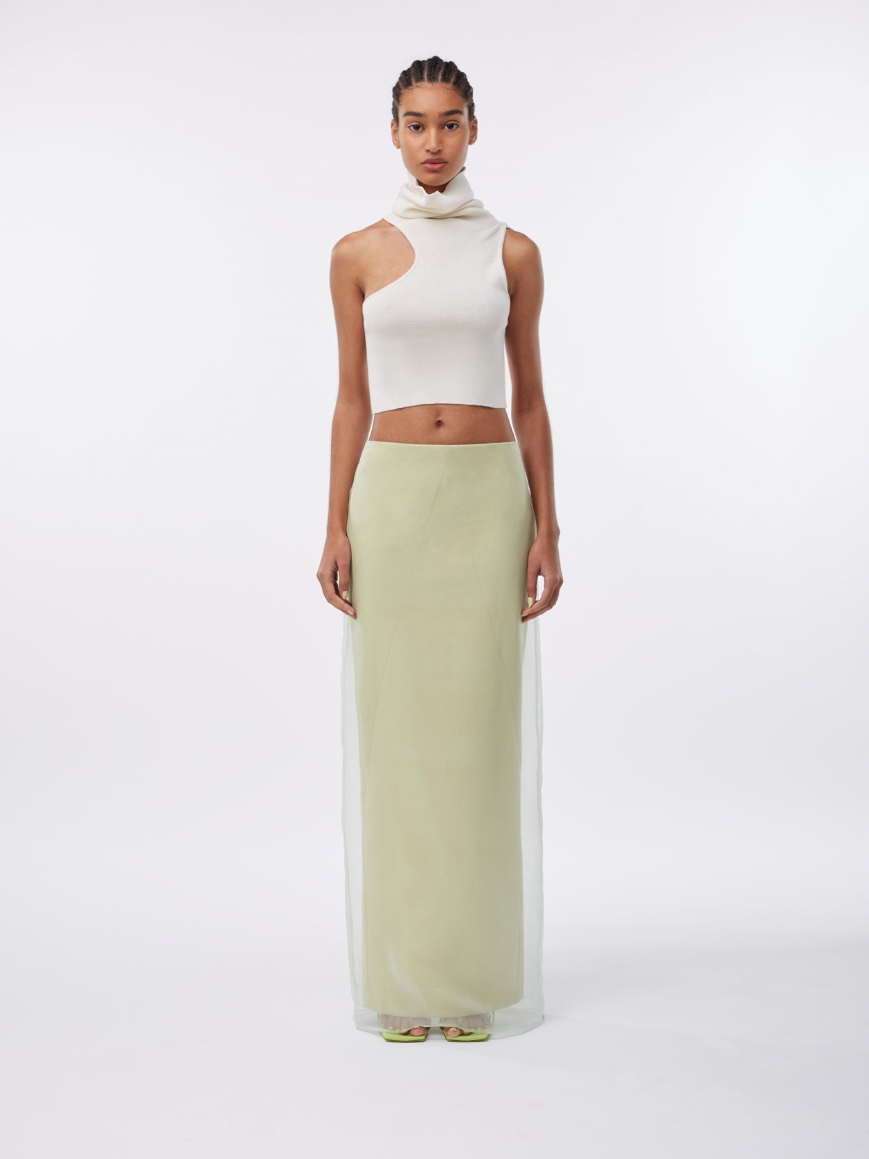 model wearing a white turtleneck wool crop top and a green pale long skirt with veil