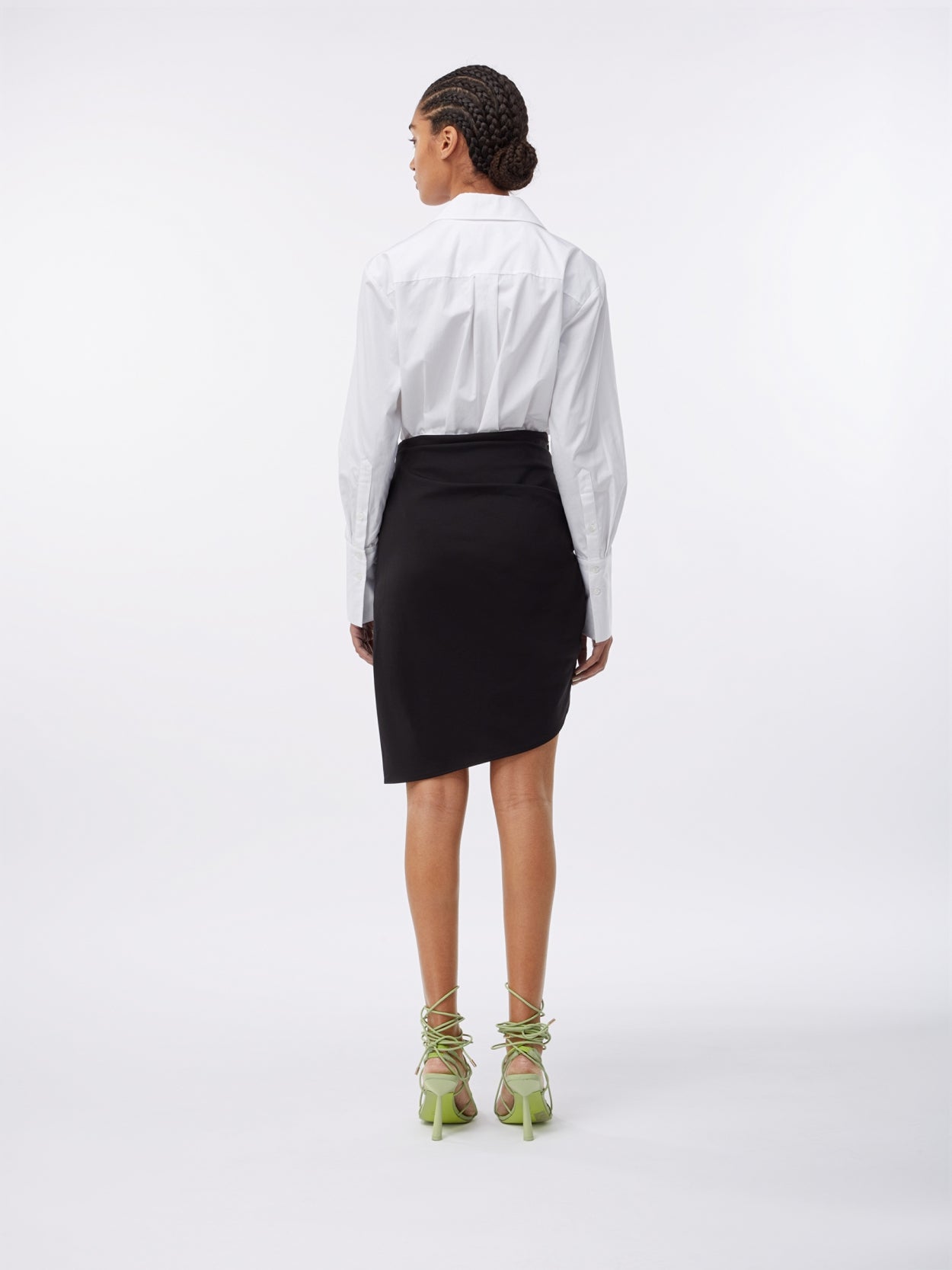 model wearing a white shirt bodysuit and a black asymmetric jersey draped skirt