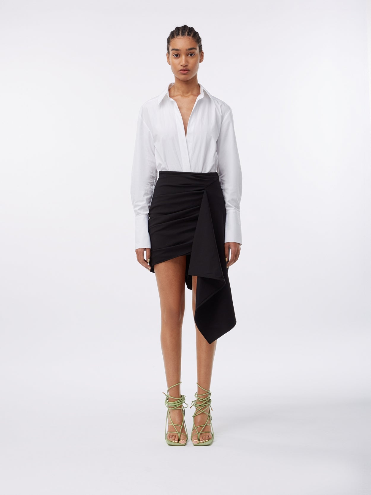 model wearing a white shirt bodysuit and a black asymmetric jersey draped skirt