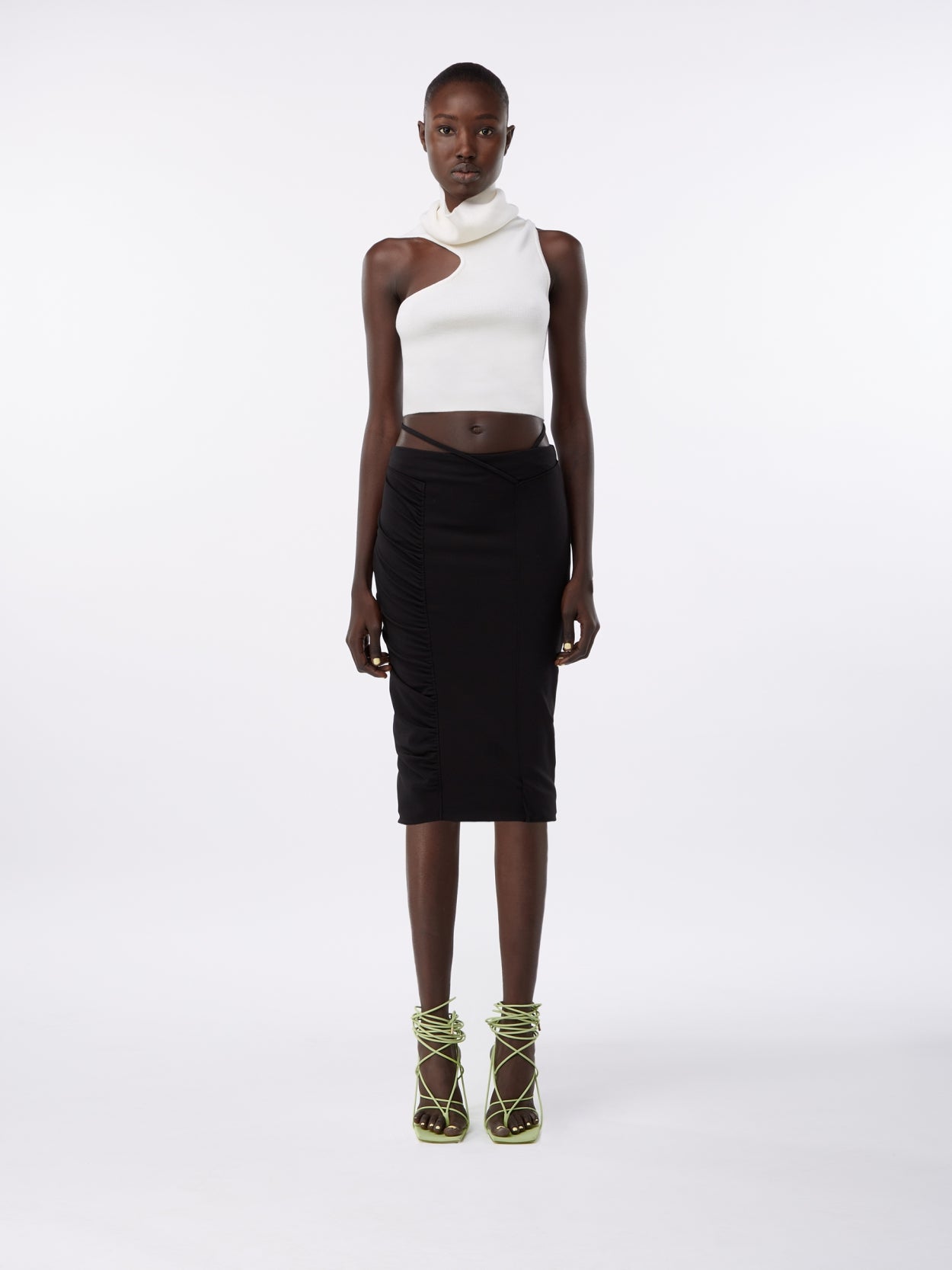model wearing a white turtleneck wool crop top and a midi pencil skirt with waist strap